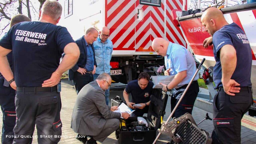 Auf dem Bild ist die Übergabe der Unterwasserdrohne zu sehen. Mehrere Personen schauen sich die Drohne in Bernau an.