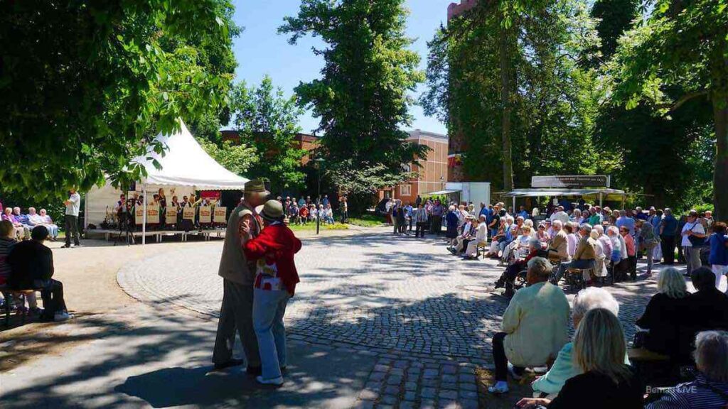 Viele Menschen tanzen zum Pfingskonzert im Bernauer Stadtpark. Im Hintergrund spielt eine Band