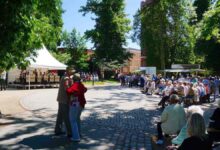 Viele Menschen tanzen zum Pfingskonzert im Bernauer Stadtpark. Im Hintergrund spielt eine Band