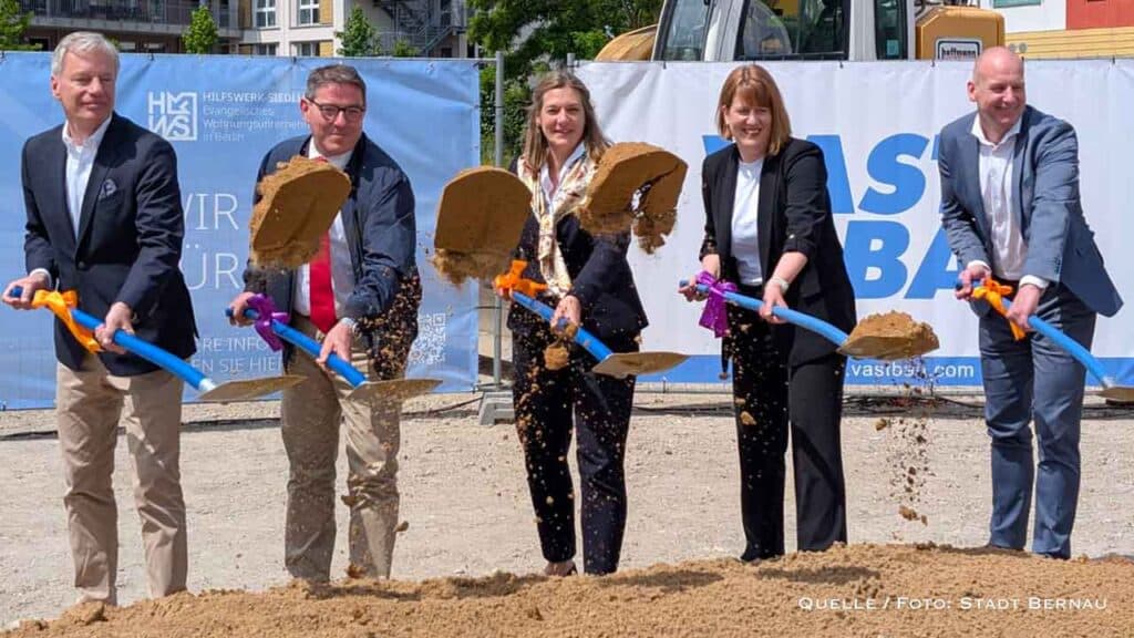 Modell vom Wohnquartier und der symbolische Spatenstich mit xy; Bürgermeister André Stahl, Dr. Viola Vogel von der EKBO, HSW-Geschäftsführerin Lena Karohs und André Bregmann von Vastbau.